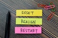 Concept of Reset, Realign, Restart write on sticky notes isolated on Wooden Table