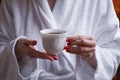 The concept of rest in a hotel. A cup in the hands of a girl in a white coat Royalty Free Stock Photo