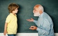 Concept of a retirement age. Elementary school teacher and student in classroom. Young boy doing his school homework Royalty Free Stock Photo