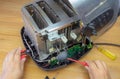 Concept Right to Repair, image showing hands of consumer repairing toaster with tools