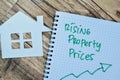 Concept of Rising Property Prices write on book isolated on Wooden Table Royalty Free Stock Photo