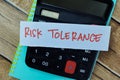 Concept of Risk Tolerance write on sticky notes with calculator isolated on Wooden Table
