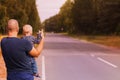 Concept of road trip. Father and son trying to stop the car on the highway. Family hitch-hiking and stopping car with thumbs up ge