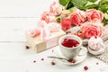 The concept of romantic tea. Wrapped gift, hibiscus tea, a bouquet of delicate roses, sweets Royalty Free Stock Photo