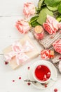 The concept of romantic tea. Wrapped gift, hibiscus tea, a bouquet of delicate roses, sweets Royalty Free Stock Photo