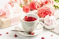 The concept of romantic tea. Wrapped gift, hibiscus tea, a bouquet of delicate roses, sweets Royalty Free Stock Photo