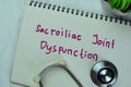 Concept of Sacroiliac Joint Dysfunction write on a book isolated on Wooden Table