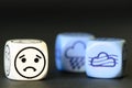 concept of sad autumn weather - emoticon and weather dice on black background