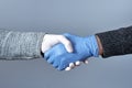 The concept of a safe handshake. Shaking hands in medical gloves on gray background