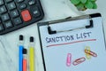 Concept of Sanction List write on a paperwork isolated on Wooden Table
