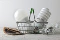 The concept of saving electricity. money and different bulbs in a basket on a light background. the choice between economical