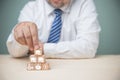 Concept saving money for buying a home, loan, from the bank. Businessman putting arranging wood block stacking on wooden table.