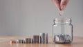 Concept of saving money for the future. Man hand putting coins in jar with money stack step growing growth saving money Royalty Free Stock Photo