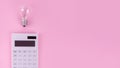 The concept of savings electricity. Reducing the payment of utility bills. A incandescent lamp, calculator on a pink background.
