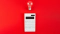 The concept of savings electricity. Reducing the payment of utility bills. A incandescent lamp, calculator on a red background.