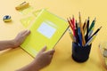 The concept of school education. A stack of yellow notebooks in the hands of a child next to various school supplies, yellow Royalty Free Stock Photo