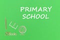 Text primary school, school supplies wooden miniatures on green background