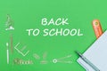 Text back to school, school supplies wooden miniatures, notebook with ruler, pen on green backboard
