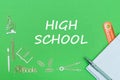 Text high school, school supplies wooden miniatures, notebook with ruler, pen on green backboard