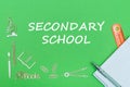 Text secondary school, school supplies wooden miniatures, notebook with ruler, pen on green backboard