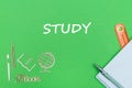 Text study, school supplies wooden miniatures, notebook on green background