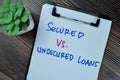 Concept of Secured Vs Unsecured Loans write on paperwork isolated on Wooden Table