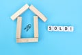 Concept of selling or buying a house or real estate. House symbol made of wooden blocks and sold word on wooden cubes with key Royalty Free Stock Photo