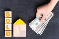 The concept of selling a house. The word SOLD on wooden cubes and the broker`s hand with dollar bills on a dark background