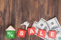 The concept of selling real estate. The word SALE on red wooden cubes, keys, a small house made of wooden blocks, dollar bills on Royalty Free Stock Photo