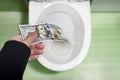 Concept of senseless waste of money, loss, useless waste, large water costs, 100 Dollar bills flushed into a toilet bowl