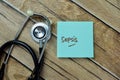 Concept of Sepsis write on sticky notes with stethoscope isolated on Wooden Table