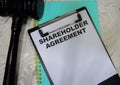 Concept of shareholder agreement write on clipboard isolated on Wooden Table Royalty Free Stock Photo