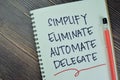Concept of Simplify, Eliminate, Automate, Delegate Productivity Advice write on a book isolated on Wooden Table