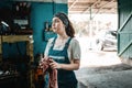 The concept of small business, feminism and women`s equality. A young woman in overalls wipes her dirty hands on a rag and looks