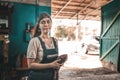 The concept of small business, feminism and women`s equality. A young woman in work clothes wipes her dirty hands on a rag