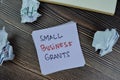 Concept of Small Business Grants write on sticky notes isolated on Wooden Table