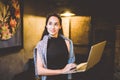 The concept of small business and technology. Young beautiful brunette businesswoman in black dress and gray sweater stands in cof Royalty Free Stock Photo