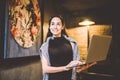 The concept of small business and technology. Young beautiful brunette businesswoman in black dress and gray sweater stands in Royalty Free Stock Photo