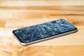 Concept of smart phone with broken screen. Top view on wooden desk background. Cracked, shattered lcd touch screen on modern Royalty Free Stock Photo