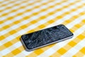 Concept of smart phone with broken screen. Top view on yellow background. Cracked, shattered lcd touch screen on modern cellphone Royalty Free Stock Photo