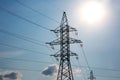 The concept of a source of electricity. Energy industry. High voltage tower with power wires against the background of the sun and