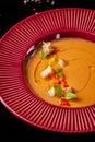 Concept of Spanish cuisine. Tomato soup Gazpacho from fresh tomatoes. Beautiful serving dishes in a red plate on a black table Royalty Free Stock Photo