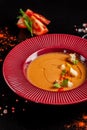 Concept of Spanish cuisine. Tomato soup Gazpacho from fresh tomatoes. Beautiful serving dishes in a red plate on a black table Royalty Free Stock Photo