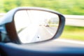 Concept of speed. Car driving on the road. Reflection in a car mirror. Rear view mirror reflection. Blurry background. Royalty Free Stock Photo