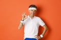 Concept of sport, fitness and lifestyle. Portrait of confident middle-aged sportsman, showing okay sign and look pleased