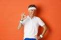 Concept of sport, fitness and lifestyle. Portrait of confident middle-aged sportsman, showing okay sign and look pleased