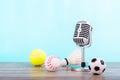 Concept sports commentator : The retro microphone put on the wooden table with football or soccer , tennis ball , baseball and