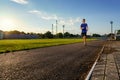 Concept of sports and health - teen boy runs along the stadium track, a soccer field with green grass Royalty Free Stock Photo