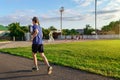 Concept of sports and health - teen boy runs along the stadium track, a soccer field with green grass Royalty Free Stock Photo