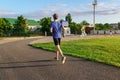 Concept of sports and health - teen boy runs along the stadium track, a soccer field with green grass Royalty Free Stock Photo